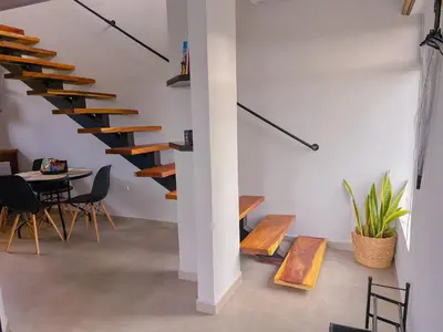 a room with a staircase and a table and chairs at Monstera Apartments Monteverde in Monteverde Costa Rica