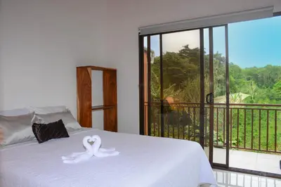 a bedroom with a white bed with a balcony at Casa Jaspe Monteverde - Balcón vista en Monteverde in Monteverde Costa Rica