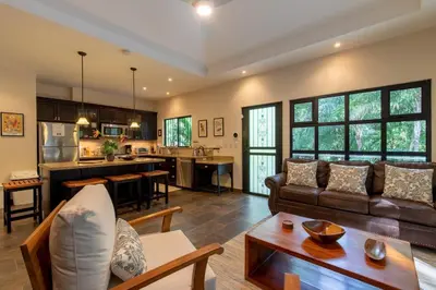 a living room with a couch and a kitchen at Four Winds Properties A Short Walk to the Beach in Nosara