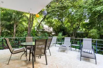 a patio with a table and chairs and trees at Four Winds Properties A Short Walk to the Beach in Nosara