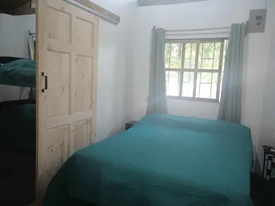 a bedroom with a green bed and a window at Blue Zone Cozy Cabaña Peaceful Getaway in Santa María