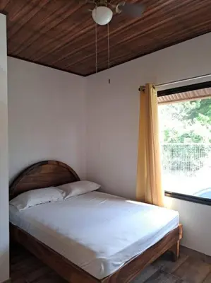 a bed in a room with a window and a bed sidx sidx at Cabinas Guacamaya Cabuya - 2 cuartos in Cabuya