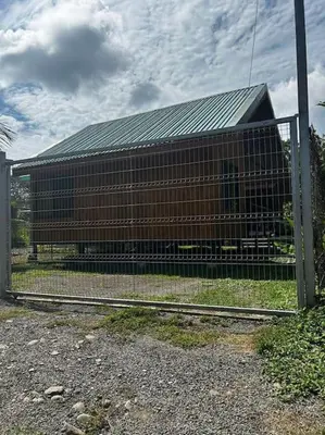 a brown building with a fence in front of it at Cabinas Guacamaya Cabuya - 2 cuartos in Cabuya