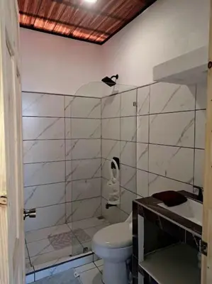a white bathroom with a toilet and a sink at Cabinas Guacamaya Cabuya - 2 cuartos in Cabuya
