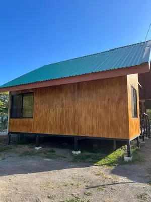 a wooden building with a green roof at Cabinas Guacamaya Cabuya - 2 cuartos in Cabuya