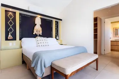 a bedroom with a large bed with a bench next to it at Casa Karibe in Tamarindo