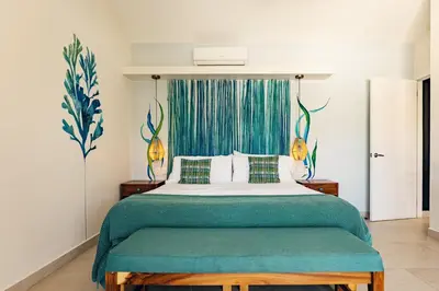 a bedroom with a large bed with a green blanket at Casa Karibe in Tamarindo