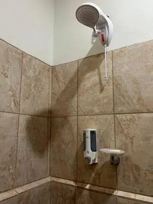 a bathroom with a shower with a hair dryer on the wall at Angel Bee Lodge in Fortuna