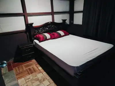 a bed with a black frame and white sheets and pillows at Posada Familiar Rìo Celeste in San Rafael