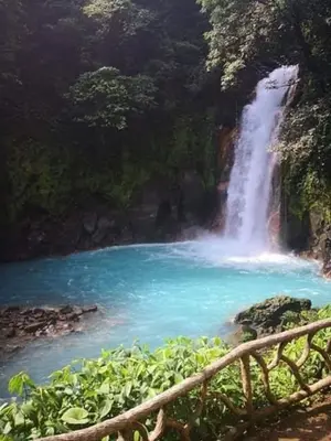 a waterfall next to a river with a bridge at Posada Familiar Rìo Celeste in San Rafael