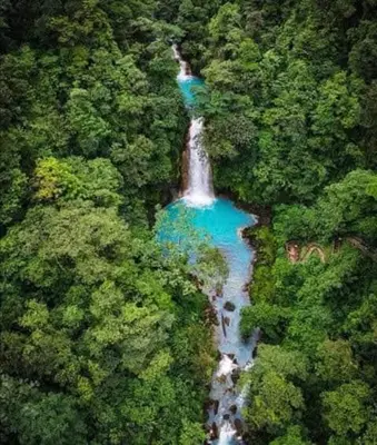an aerial view of a waterfall in the middle of a forest at Posada Familiar Rìo Celeste in San Rafael