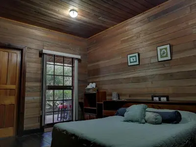 a bedroom with wooden walls with a bed and a window at Finca Queveri in Orosí
