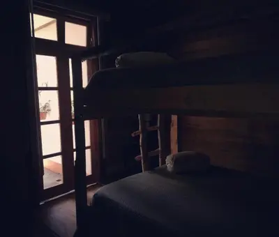 a room with three bunk beds and a window at Finca Queveri in Orosí