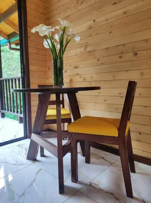 a table and two chairs and a vase with flowers at Cabinas El Quetzal in San Gerardo de Dota