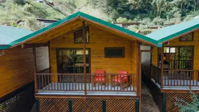 a log cabin with red chairs on the porch at Cabinas El Quetzal in San Gerardo de Dota