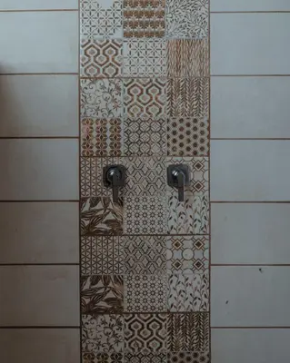 a shower with a tile wall with two handles at Cabinas El Quetzal in San Gerardo de Dota