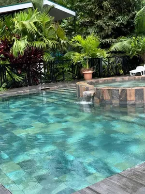 a swimming pool with blue water and a fountain at Bungalows at Residencias Arenal in Fortuna