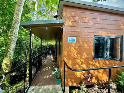 a wooden cabin with a porch and a balcony at Bungalows at Residencias Arenal in Fortuna