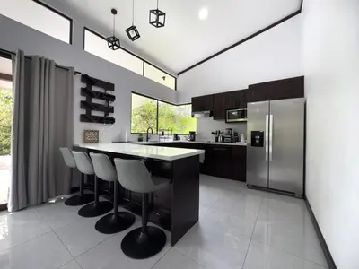 a kitchen with a island with bar stools and a refrigerator at Oro Verde Lodge in Fortuna