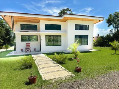 a white house with a red chair in the yard at Oro Verde Lodge in Fortuna