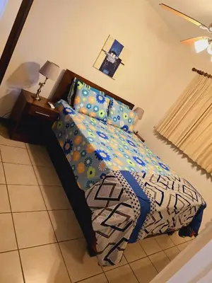 a bedroom with a bed with colorful sheets and a lamp at Condominio Coco Marindo #34 in Coco