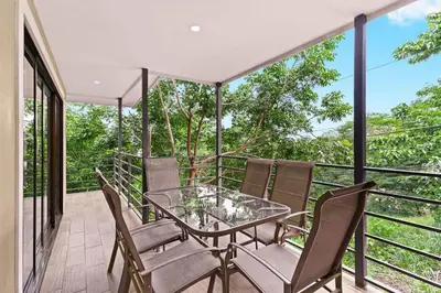 a glass table and chairs on a balcony at Charming Apartment Steps to the Beach in Tamarindo