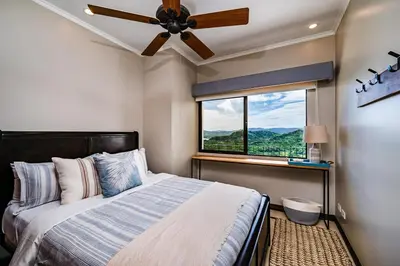 a bedroom with a bed with a ceiling fan and a window at Ocean-Views, Infinity Pools & Private Veranda in Playa Flamingo