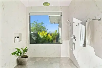 a white bathroom with a shower and a window at Infinity Edge Pool Oceanview 4 BR 4BA in Brasilito