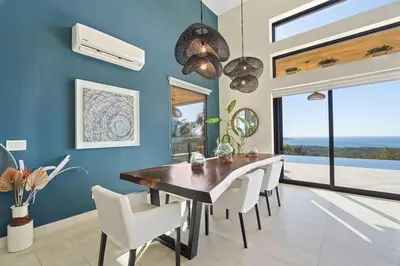 a dining room with a wooden table and white chairs at Infinity Edge Pool Oceanview 4 BR 4BA in Brasilito