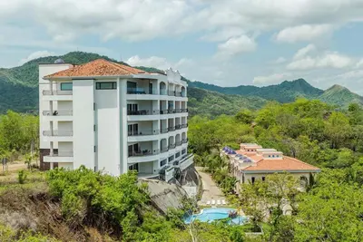 a building on a hill next to a resort at Spectacular Ocean View Condo in Playa Flamingo