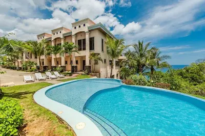 a large house with a swimming pool in front of it at Spectacular Ocean View Condo in Playa Flamingo