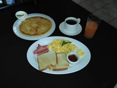 a table with two plates of breakfast food and a pizza at Hotel Wagelia Turrialba in Turrialba