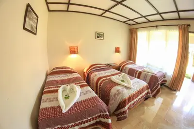 a group of three beds in a room at Hotel Wagelia Turrialba in Turrialba