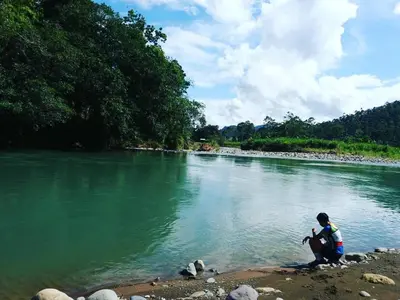 a person sitting on the shore of a river at Hotel Wagelia Turrialba in Turrialba