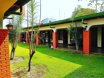 a building with a yard with two trees in it at Hotel Wagelia Turrialba in Turrialba