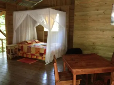 a bedroom with a bed and a table in a cabin at Hotel Wagelia Espino Blanco in Turrialba