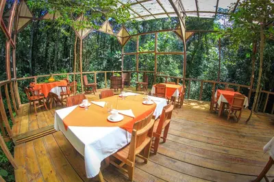 a restaurant with tables and chairs on a wooden deck at Hotel Wagelia Espino Blanco in Turrialba