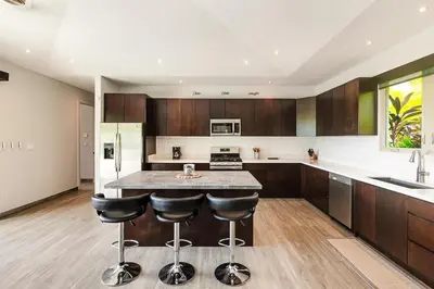 a kitchen with wooden cabinets and a island with bar stools at Contemporary Villa 3 BD 3BA Pool in Playa Flamingo