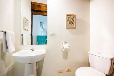 a white bathroom with a toilet and a sink at Lush Jungle Paradise - Walk to Beach in Potrero