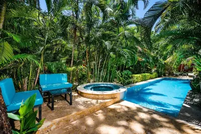 a swimming pool with two blue chairs next to a swimming pool at Lush Jungle Paradise - Walk to Beach in Potrero