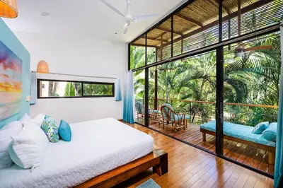 a bedroom with a bed and a large window at Lush Jungle Paradise - Walk to Beach in Potrero