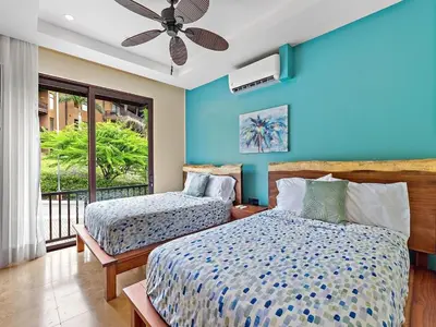 a bedroom with two beds and a blue wall at Spacious Ocean View 3 bd Condo w - Pool in Ocotal