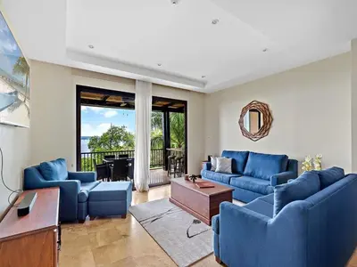 a living room with blue couches and a table at Spacious Ocean View 3 bd Condo w - Pool in Ocotal