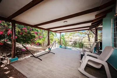 a porch with two chairs and a hammock on it at Studio, Free Concierge & Walk to Tamarindo Beach in Tamarindo
