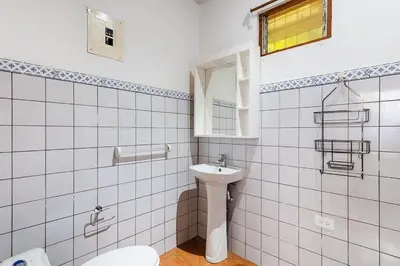 a white tiled bathroom with a toilet and a sink at Studio, Free Concierge & Walk to Tamarindo Beach in Tamarindo