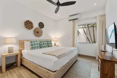 a bedroom with a bed and a desk and a television at 7 min walk to Surfing Paradise, Pool & Ocean Fun in Playa Grande
