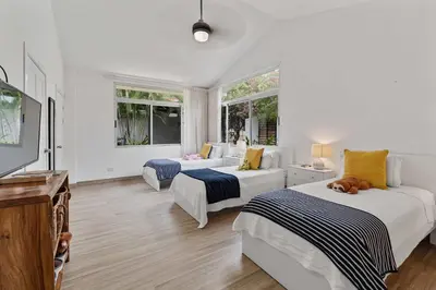 two beds in a white room with windows at 7 min walk to Surfing Paradise, Pool & Ocean Fun in Playa Grande