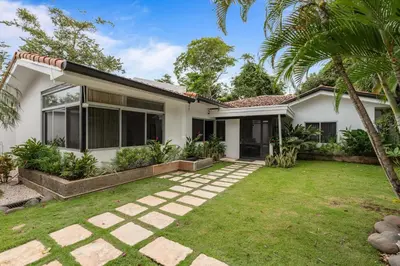 a white house with a lawn in front of it at 7 min walk to Surfing Paradise, Pool & Ocean Fun in Playa Grande