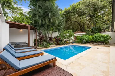 a pool with two lounge chairs next to a house at 7 min walk to Surfing Paradise, Pool & Ocean Fun in Playa Grande