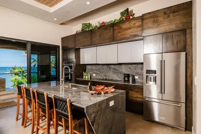 a kitchen with a large island with chairs and a refrigerator at Beachfront Luxury Villa, 2 Pools & Daily Breakfast in Playa Flamingo